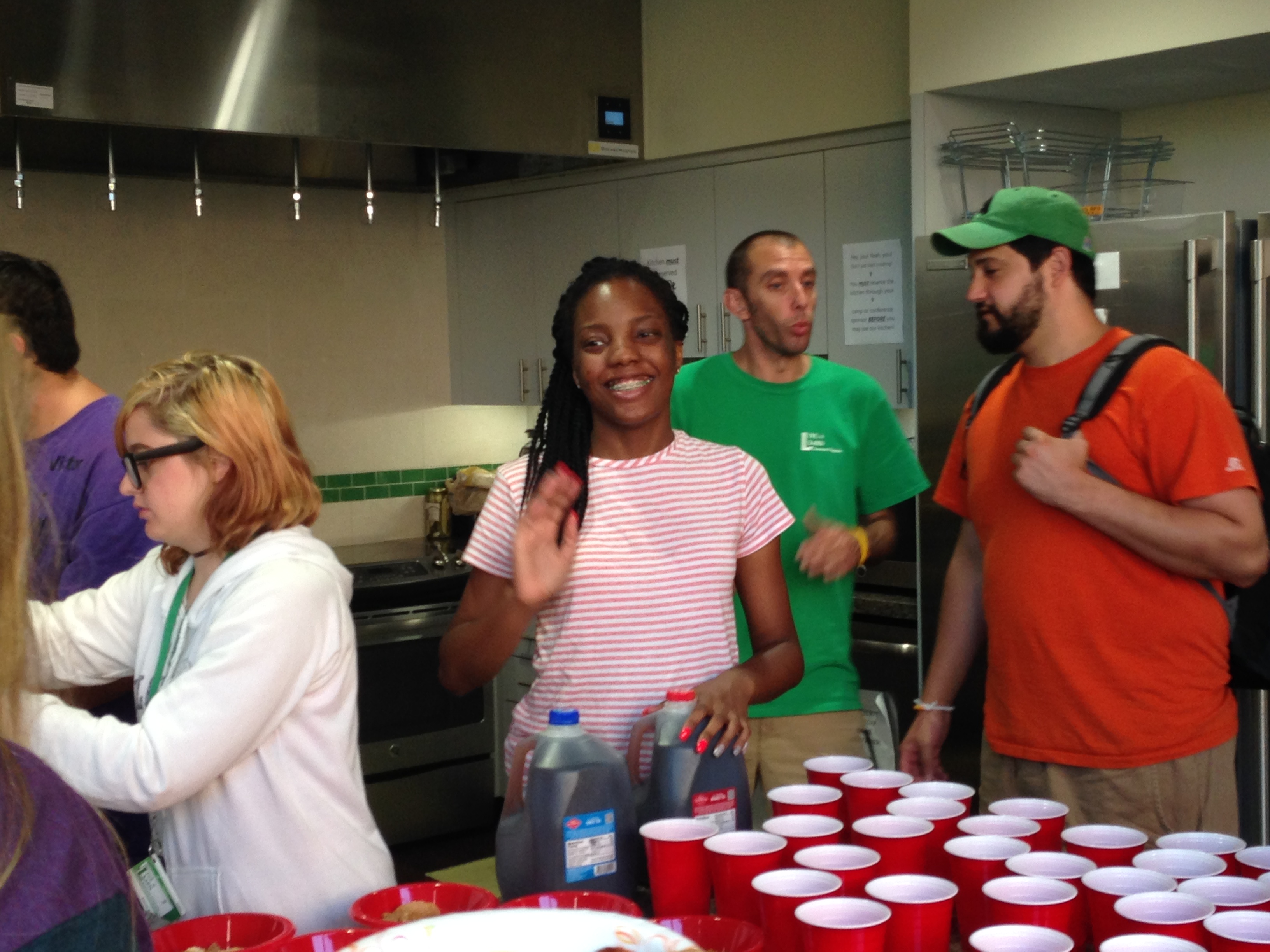 Participant waving and smiling, while filling up red cups. 