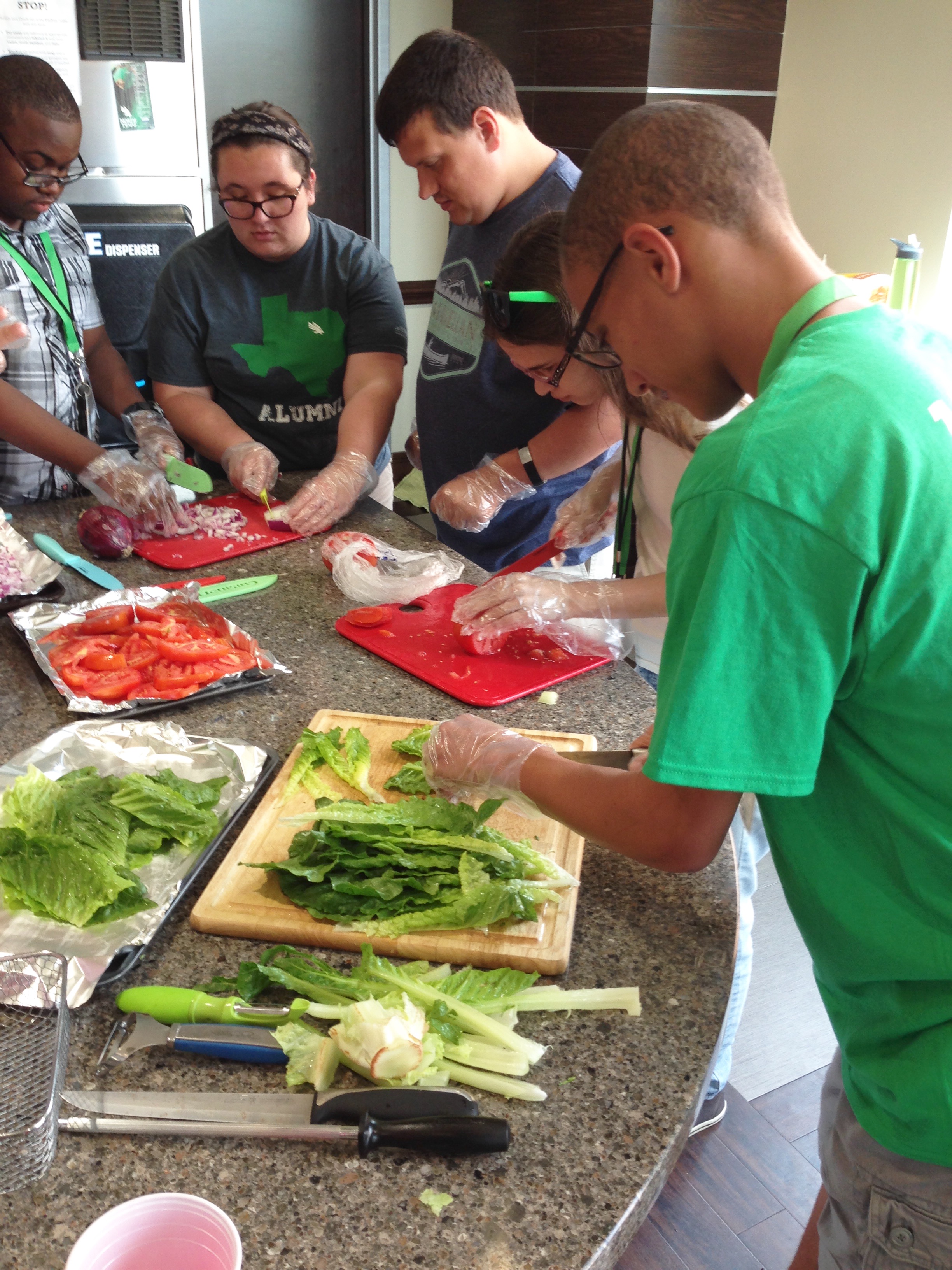 Three participants and one staff preparing vegetables, by chopping.