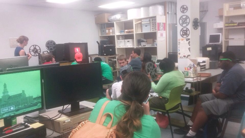 Group of participants in a media lab, listening to a guest speaker. 